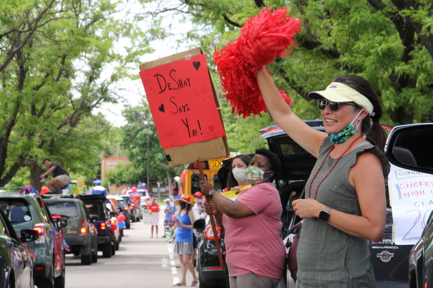 Stephany Shadwell, right, a Cherry Creek High School English teacher, waves a pompom as graduating seniors cruise by June 4 for a drive-thru senior parade. Hundreds of cars rolled through the path — around the perimeter of the campus — for more than two hours.
